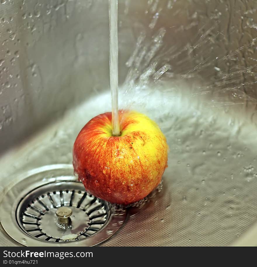 Apple and water splashes in a sink