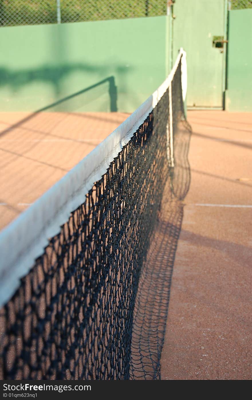 A clay court and the net of tennis. A clay court and the net of tennis