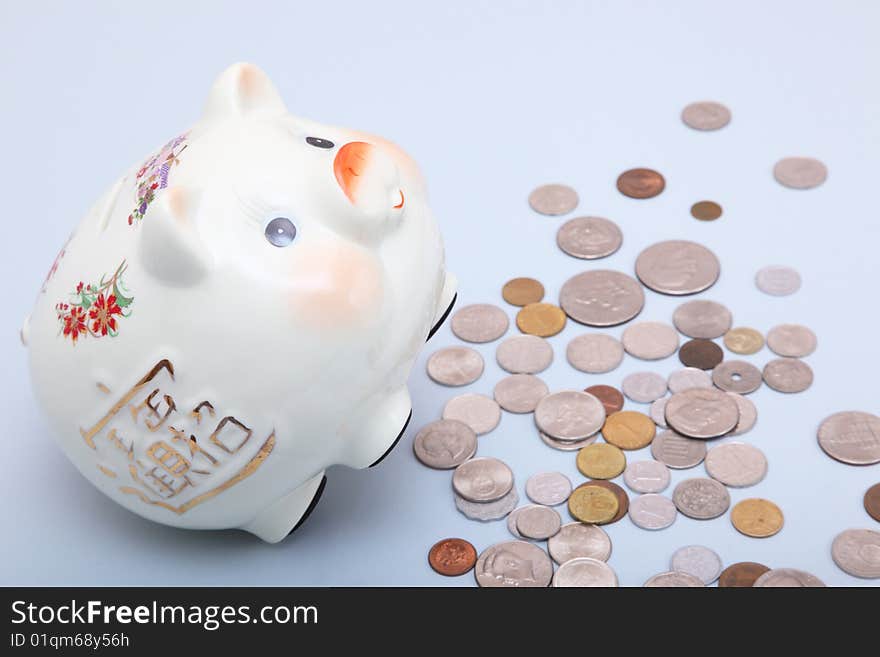 Piggy bank with coins on a light blue background