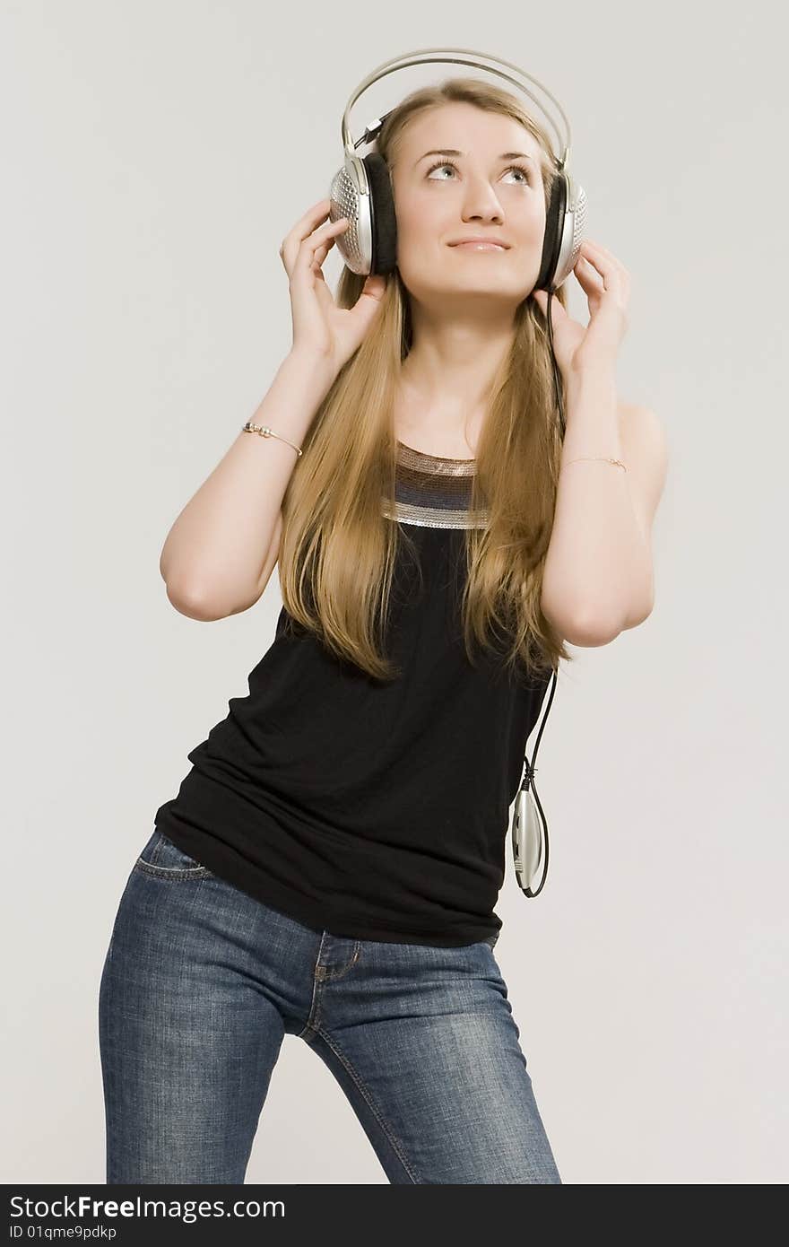 Young girl a blonde listens music through earpiecess