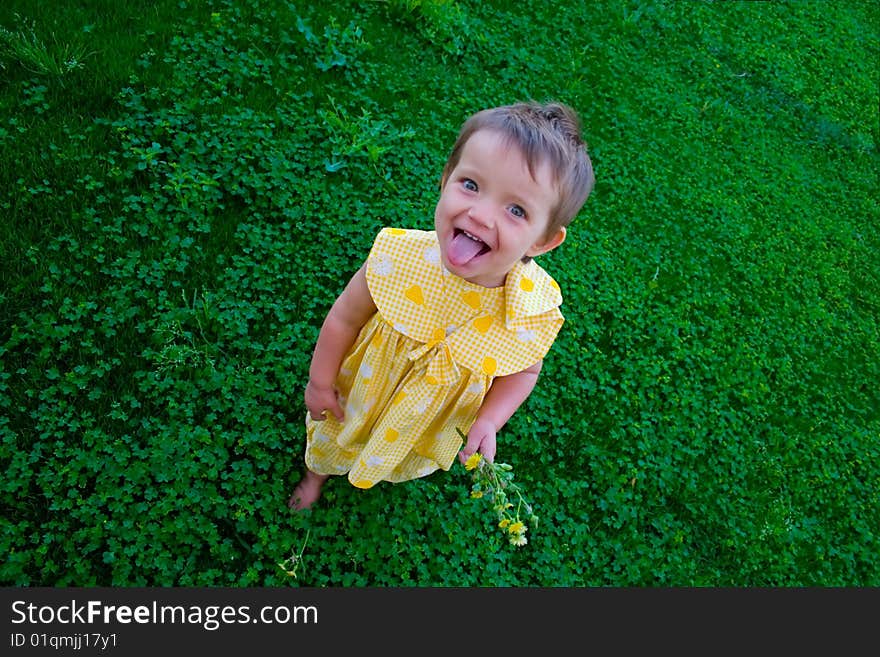 Portrait of little girl putting out her tongue on grass background. Portrait of little girl putting out her tongue on grass background