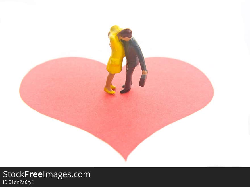 Miniature figures embracing on a red heart. Miniature figures embracing on a red heart.