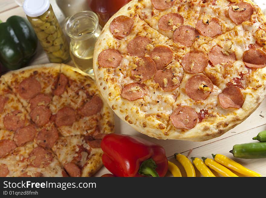 A couple of delicious pizzas, with raw tomatoes, green peppers and salami. A couple of delicious pizzas, with raw tomatoes, green peppers and salami