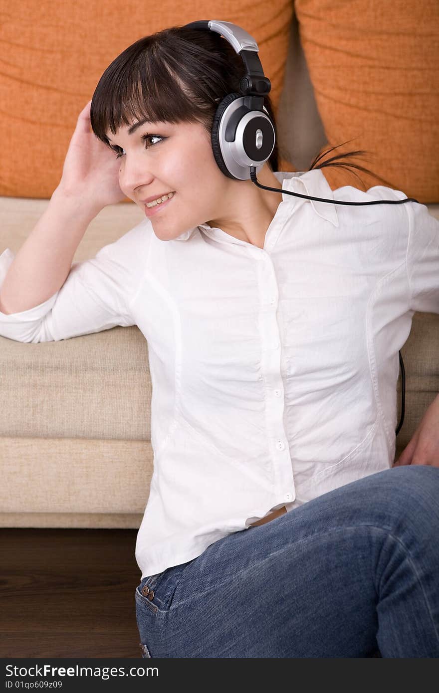 Attractive brunette woman with headphones sitting on floor. Attractive brunette woman with headphones sitting on floor