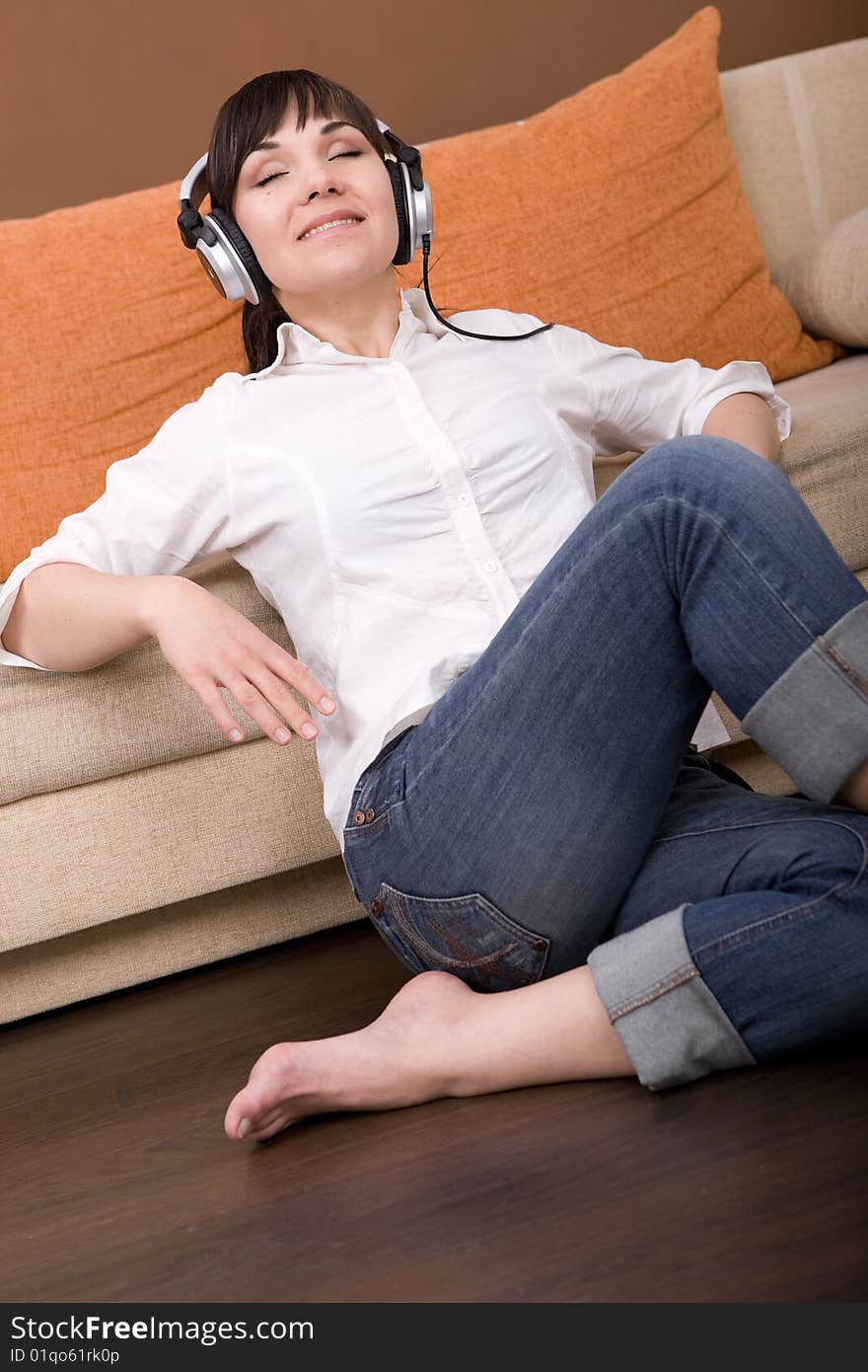 Attractive brunette woman with headphones sitting on floor. Attractive brunette woman with headphones sitting on floor