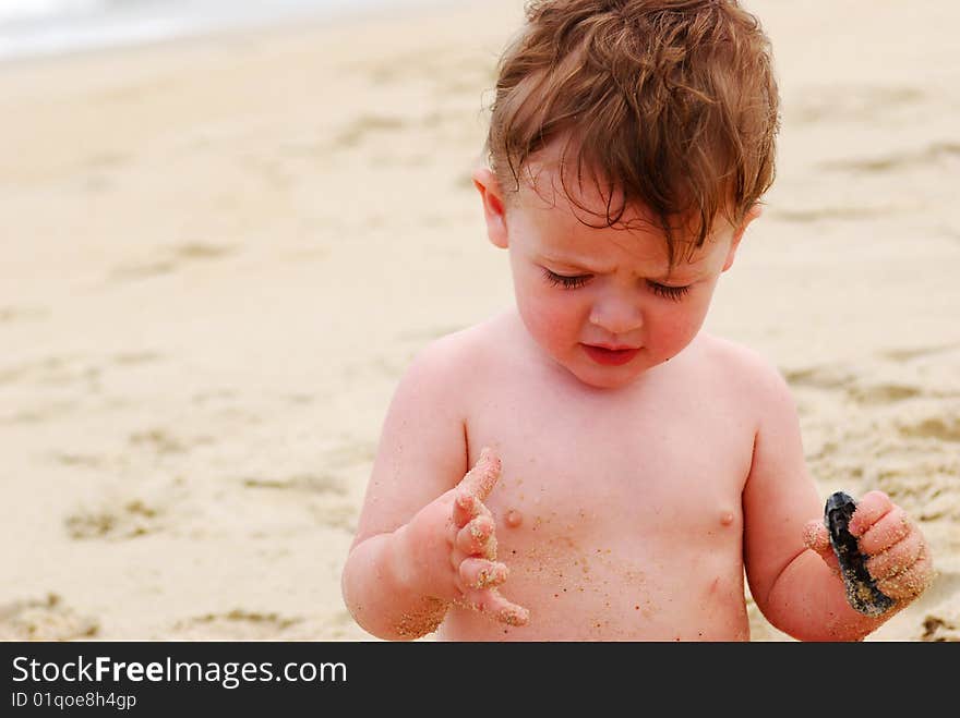 A cute baby boy playing in the sand