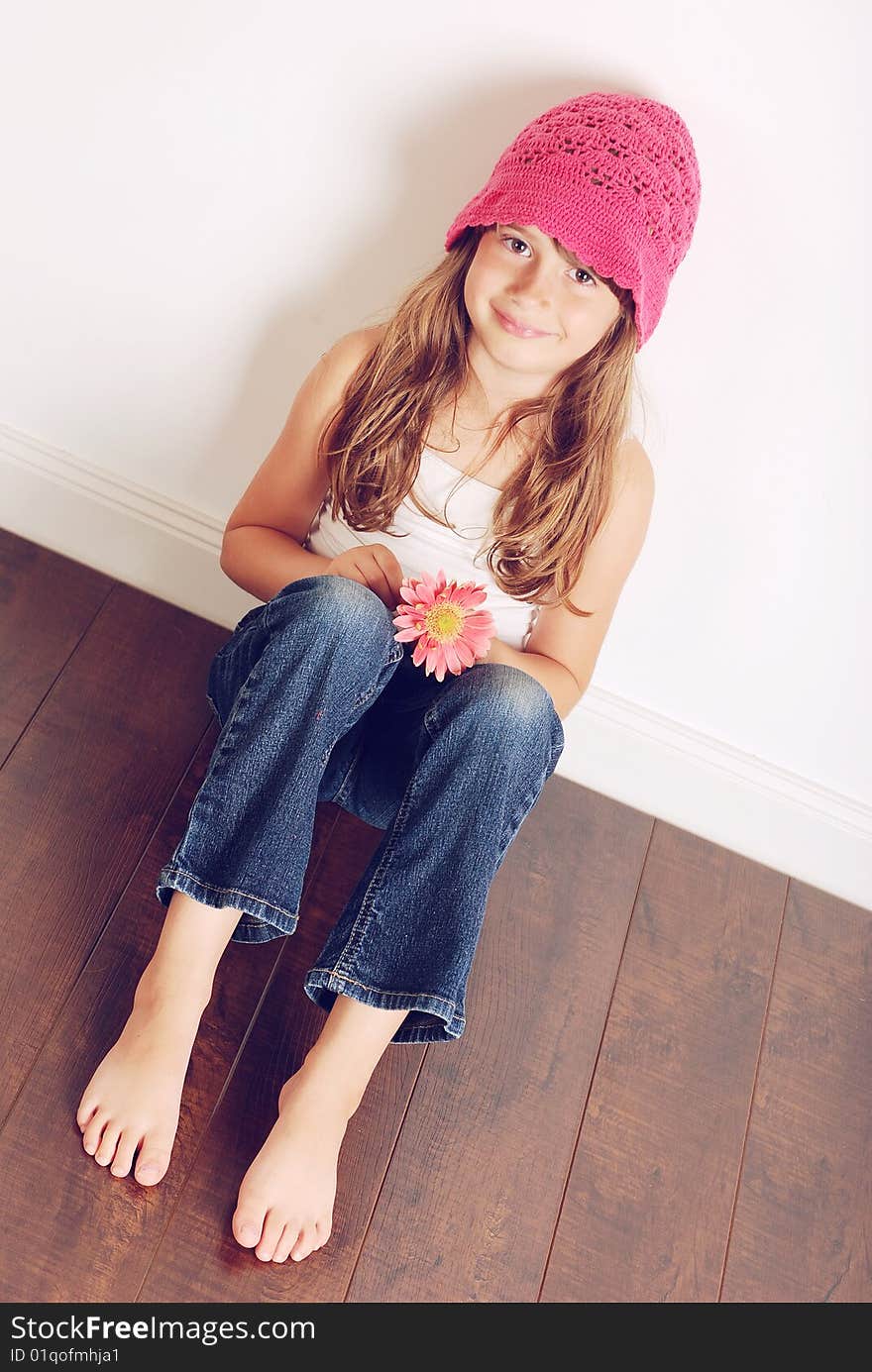 A cute young girl sitting with a flower. A cute young girl sitting with a flower