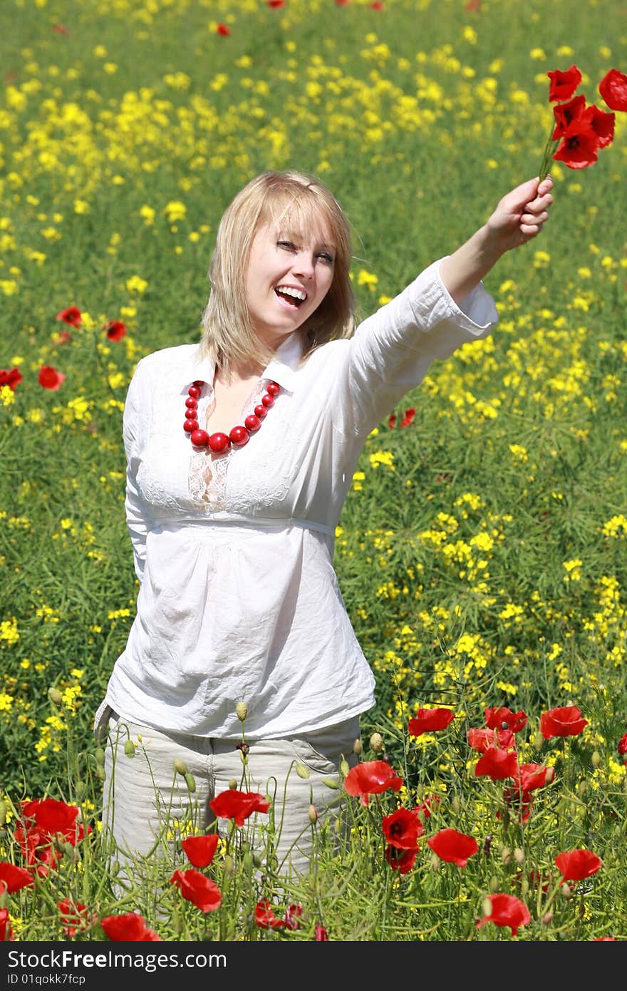 The blonde on the meadow assembles red poppies. The blonde on the meadow assembles red poppies