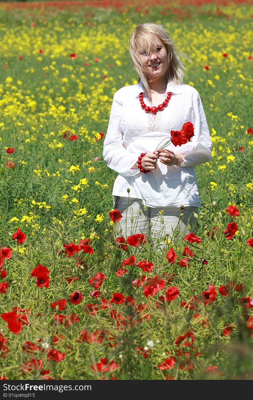 The blonde on the meadow assembles red poppies. The blonde on the meadow assembles red poppies