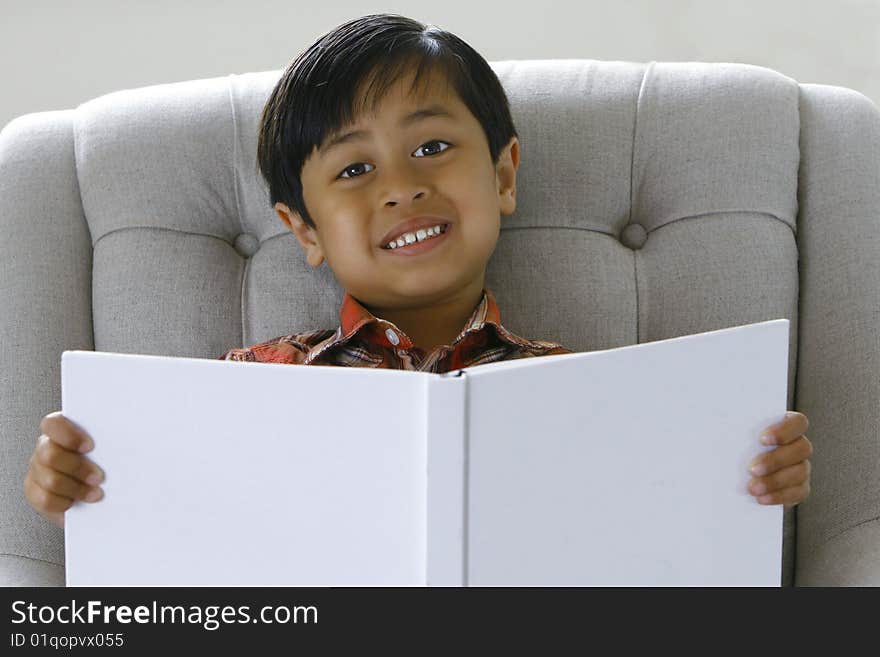 A 5 year old boy (asian origin) smiling while holding a book. A 5 year old boy (asian origin) smiling while holding a book.