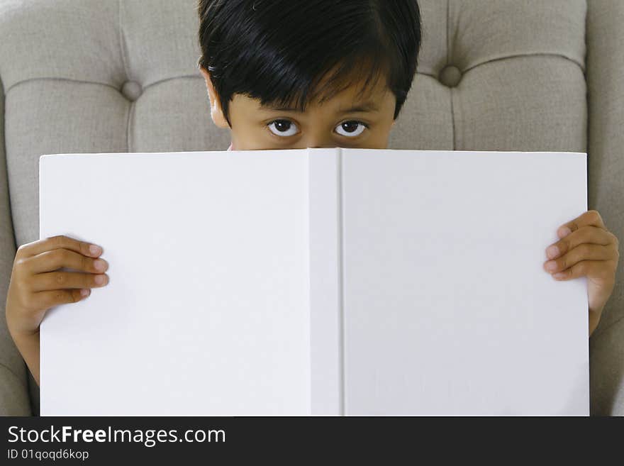 A 5 year old boy (asian origin) reading a book. A 5 year old boy (asian origin) reading a book.