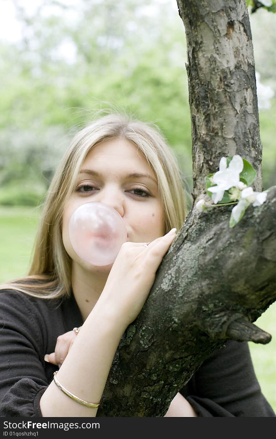 Playful blond girl blowing bubble with bubble gum. Playful blond girl blowing bubble with bubble gum