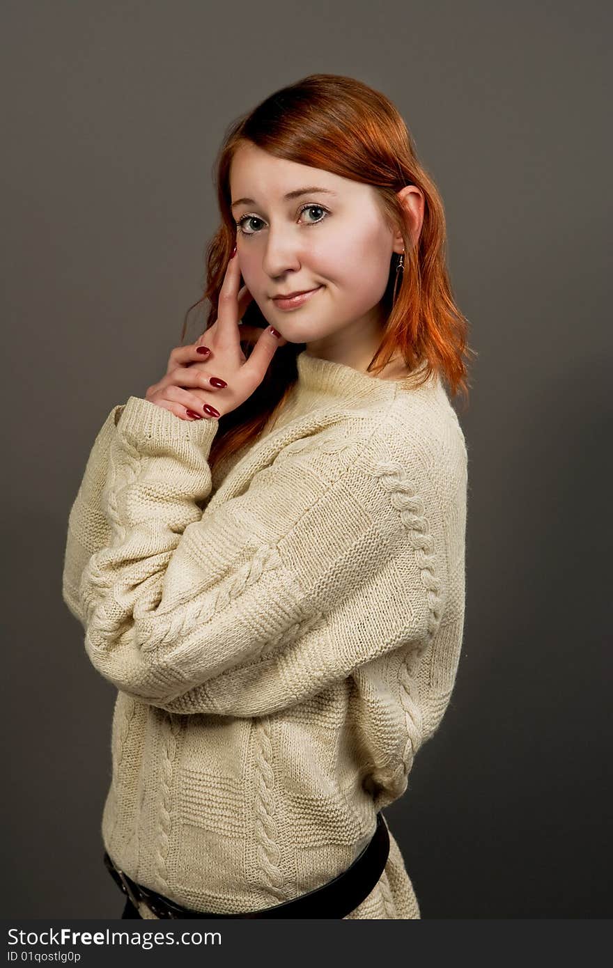 Red haired girl in sweater turned isolated over gray