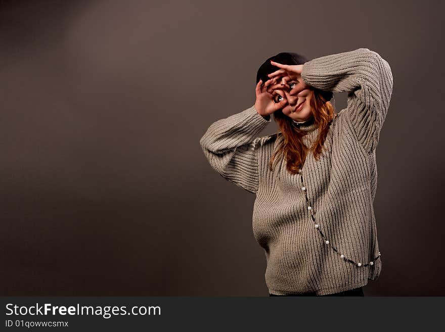 Pretty young woman making glasses isolated over grey