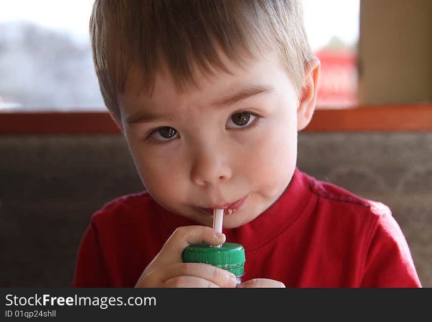 A young boy drinking juice through a straw.