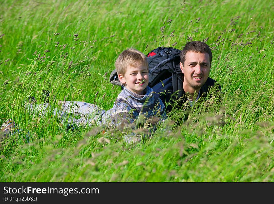 The man and the boy lie in a grass and smile. The man and the boy lie in a grass and smile