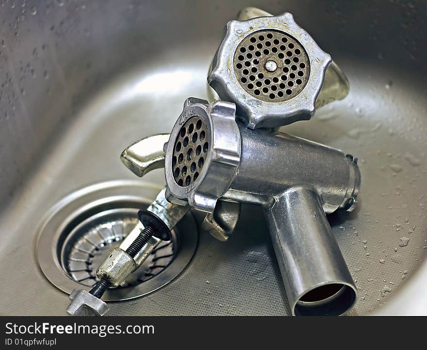 Two meat grinders in a stainless steel sink