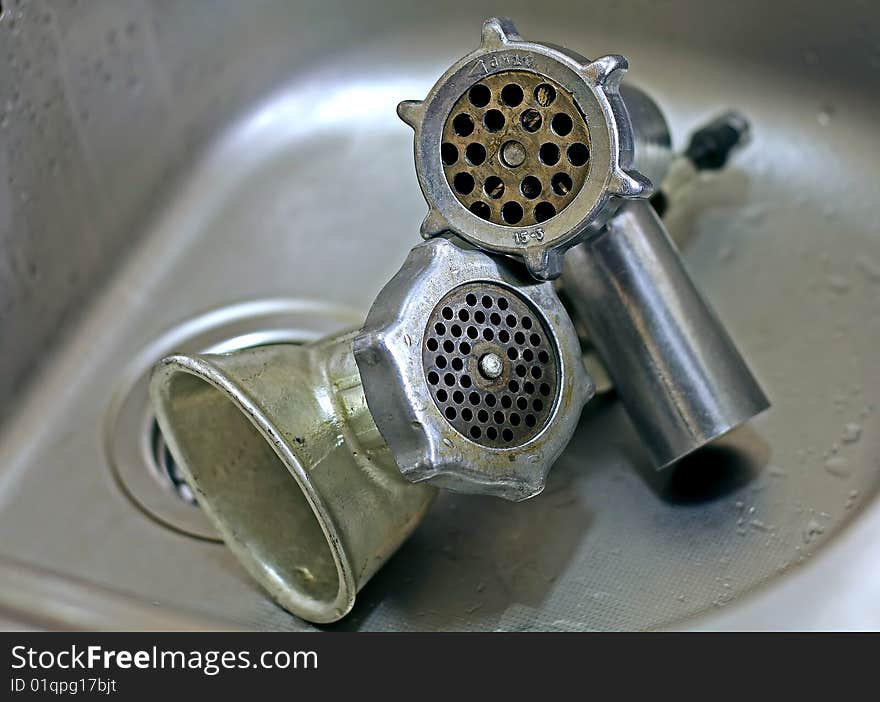 Two meat grinders in a sink