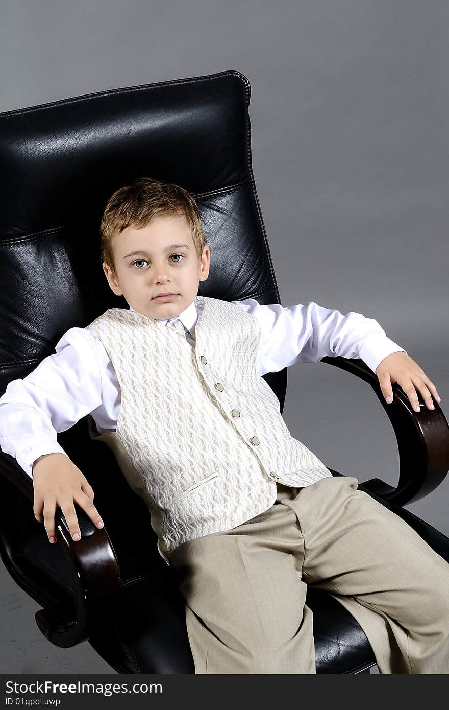 Close-up of small boy sitting on chair in office. Close-up of small boy sitting on chair in office