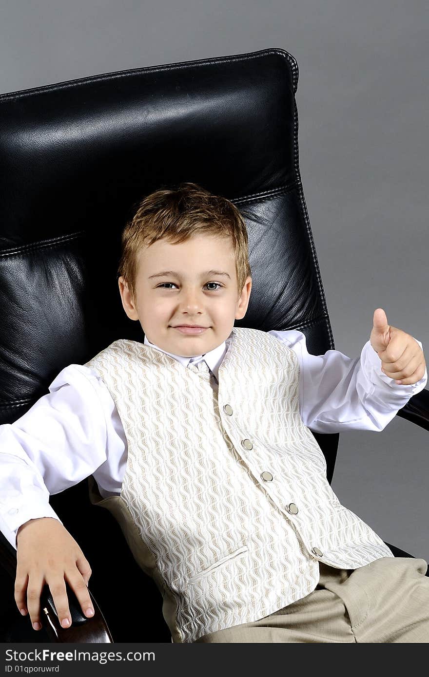 Close-up of small boy sitting on chair in office. Close-up of small boy sitting on chair in office