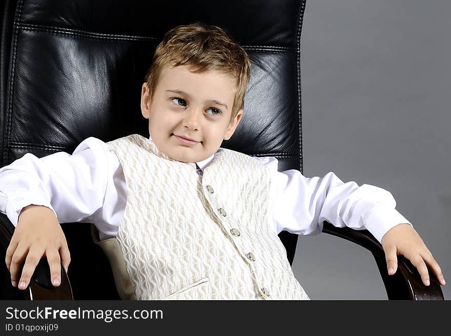 Close-up of small boy sitting on chair in office. Close-up of small boy sitting on chair in office