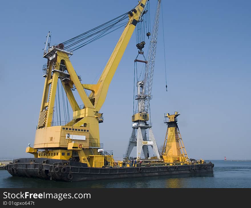 Swimming crane transporting another crane to a dock