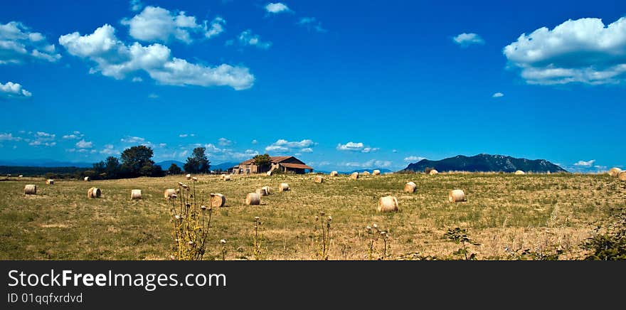 Bales of hay arount the farm and the mountains on the background