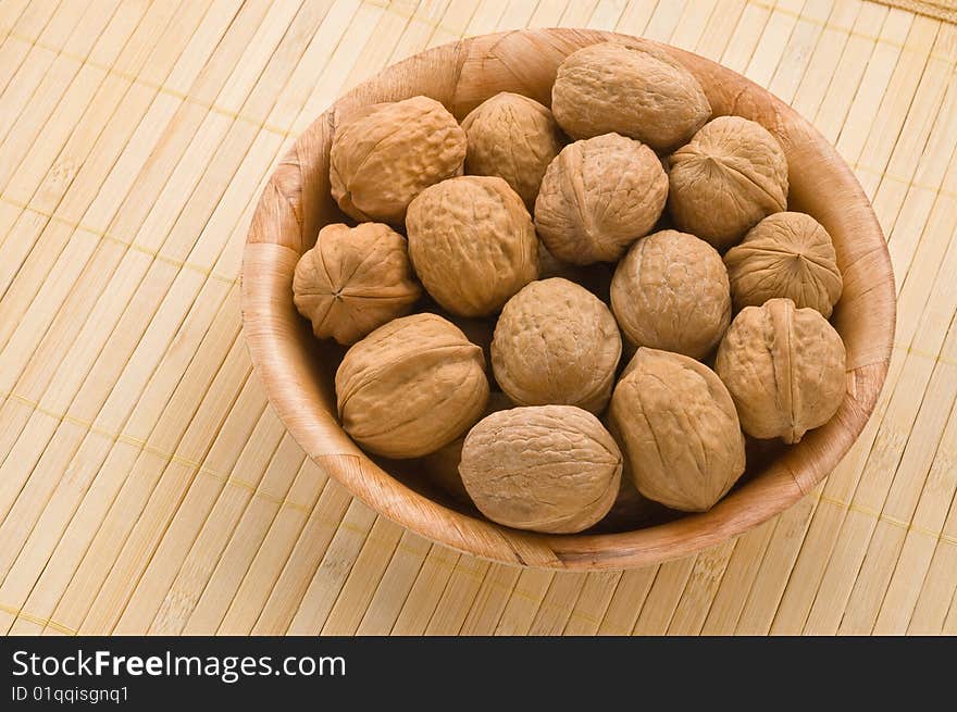 Bunch of walnuts in a bowl, over a bamboo mat. Bunch of walnuts in a bowl, over a bamboo mat.