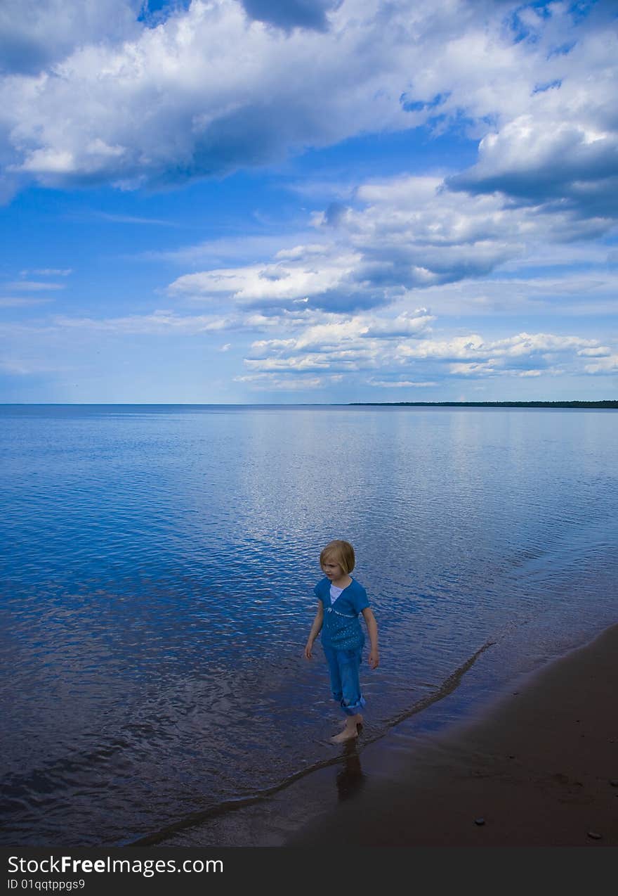 Child, clouds, beach, and blue reflecting water on Wisconsin Point along the shore of Lake Superior