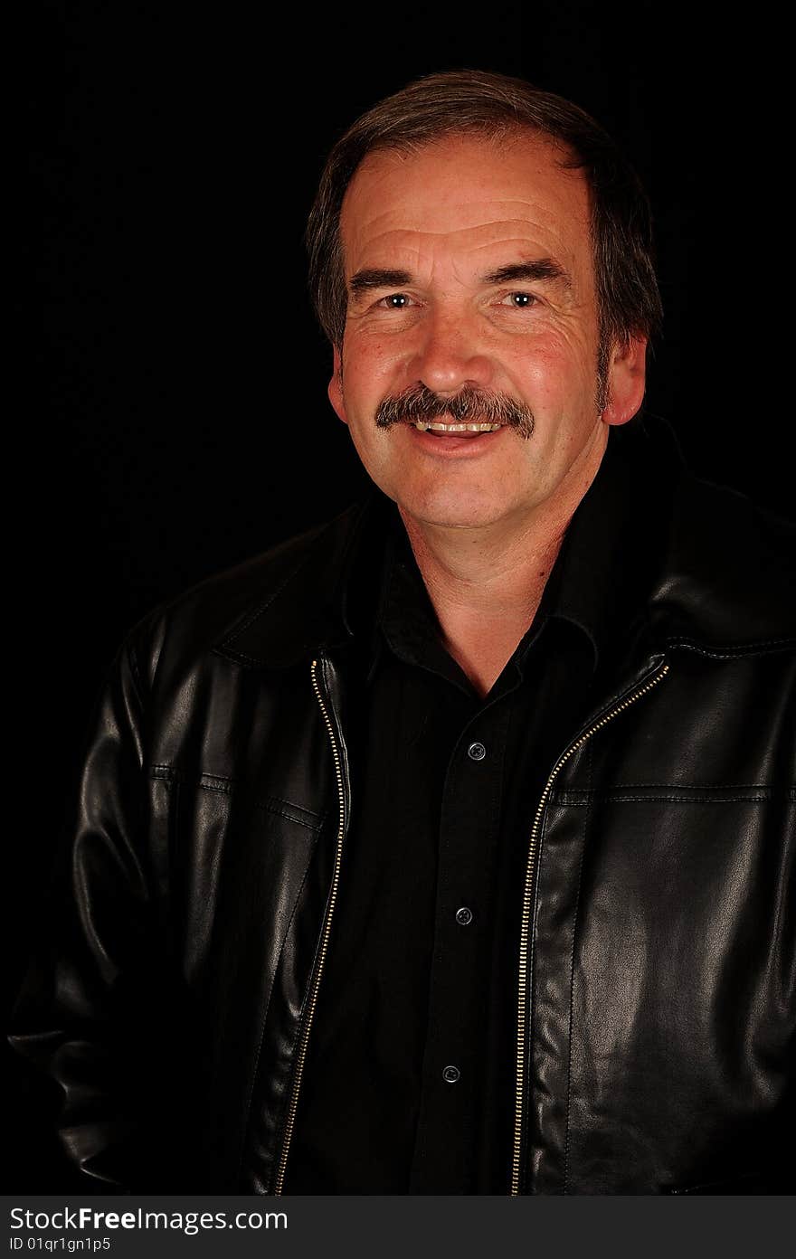 A smiling man on a black studio back ground