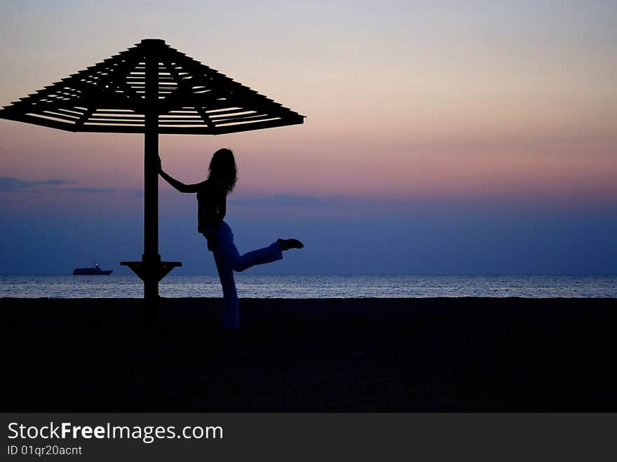 Beach umbrella and the girl silhouette on sunset. Beach umbrella and the girl silhouette on sunset