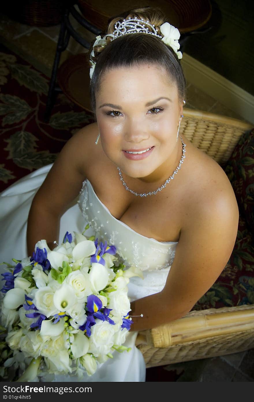 A beautiful smiling bride seated in a strapless dress holding flowers. A beautiful smiling bride seated in a strapless dress holding flowers.