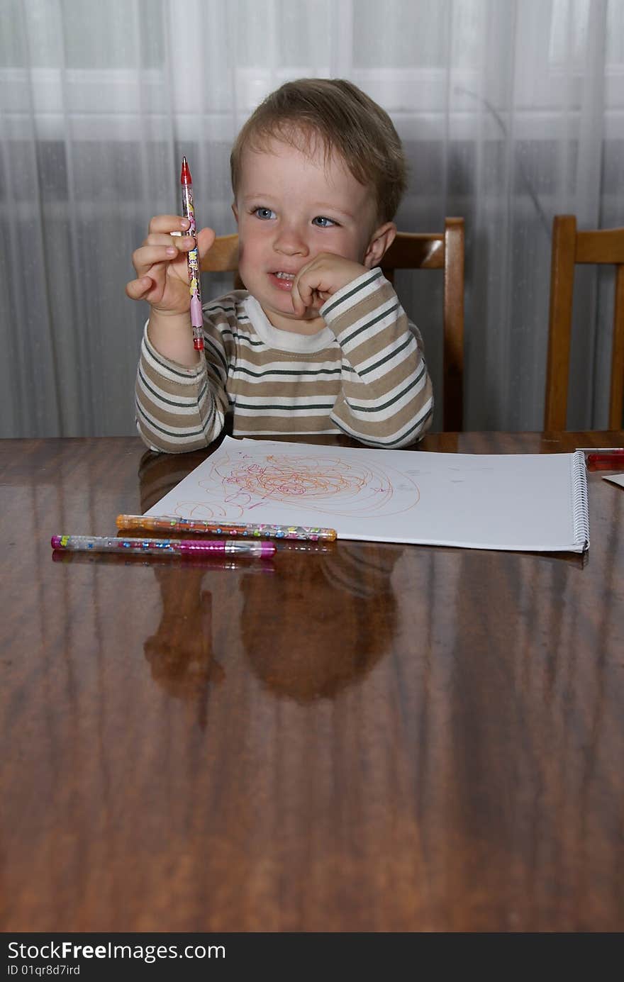 A boy paints on a sheet of paper. A boy paints on a sheet of paper