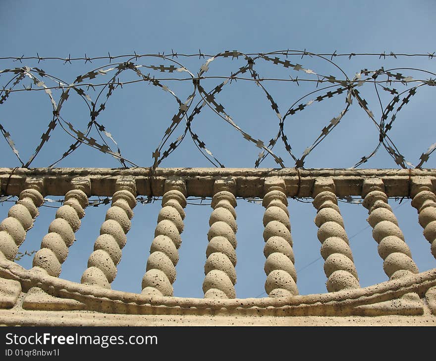 Barbwire and wall under blue sky