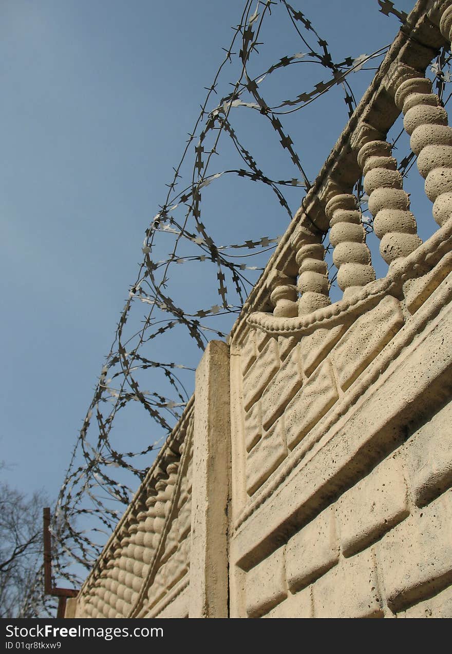 Barbwire and wall under blue sky