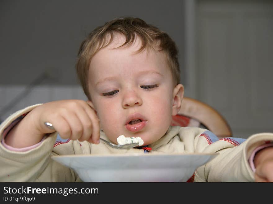 Boy reluctantly eats spoon cheese. Boy reluctantly eats spoon cheese