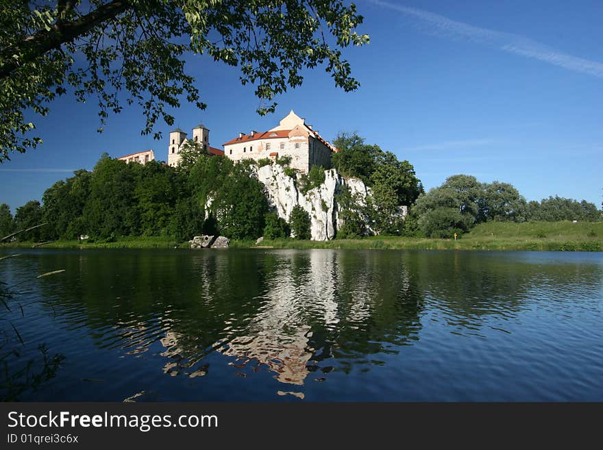 Benedictine Abbey in Tyniec near Cracow in Poland (Krakow). Monastery has been built on rocks above Vistula river in 1044. Monastry mirrors in a river and the tree hangs above the building.