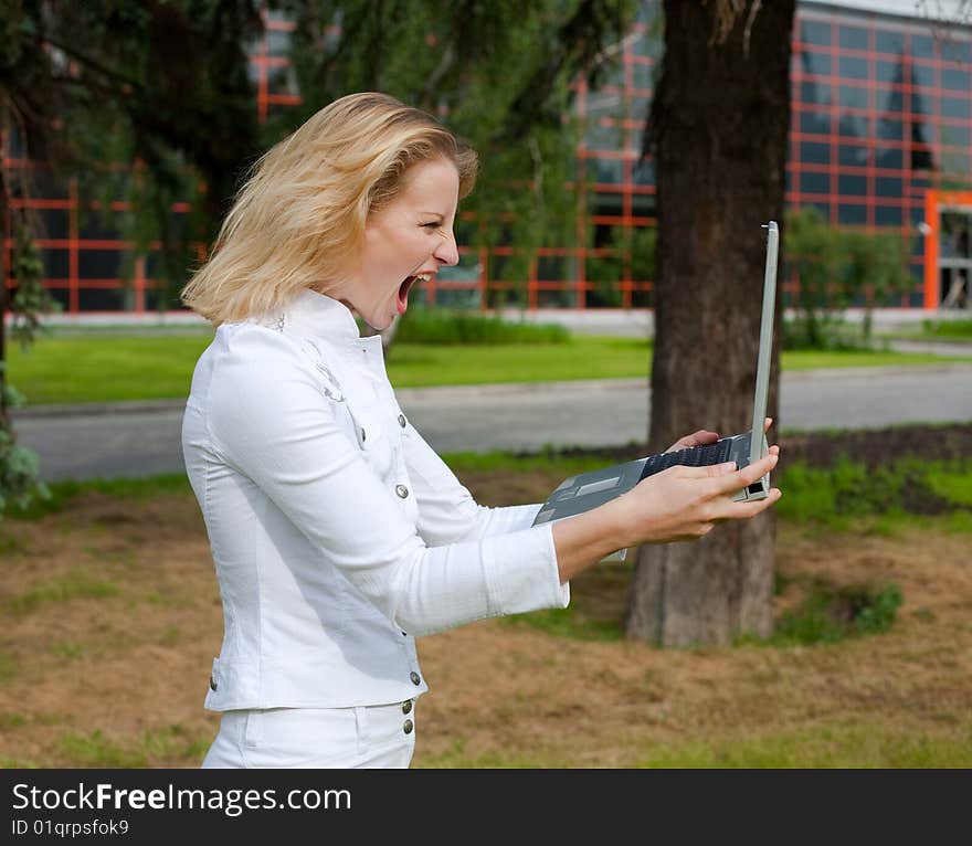 Young woman in a white suit holds a laptop and shouts on it. Young woman in a white suit holds a laptop and shouts on it