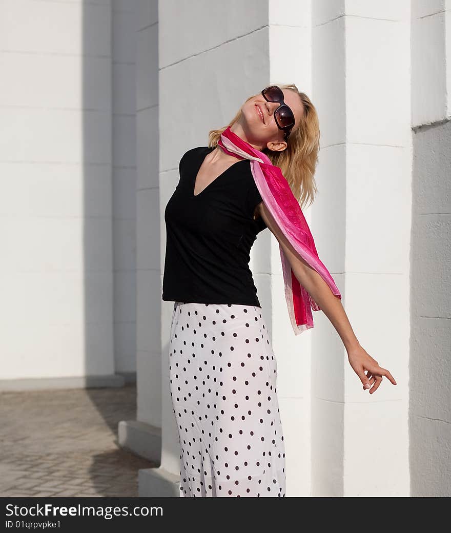 Romantic girl stays close against the wall and turns towards the sun