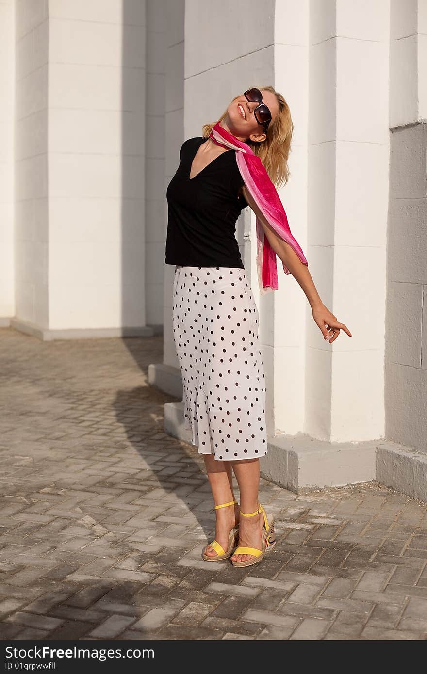 Romantic girl stays close against the wall and turns towards the sun