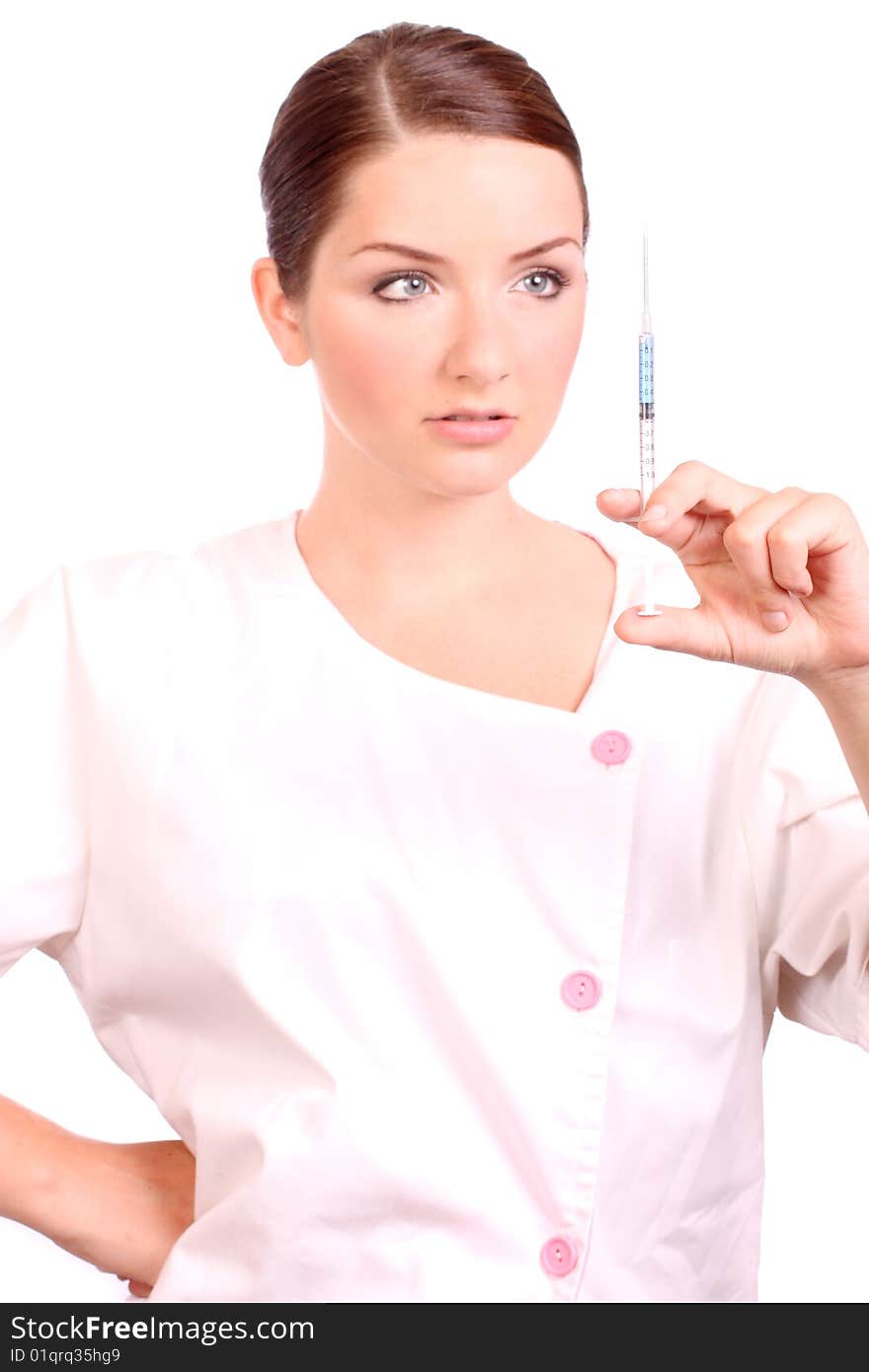 A beautiful young nurse holding a syringe and looking at it on a white background. A beautiful young nurse holding a syringe and looking at it on a white background.