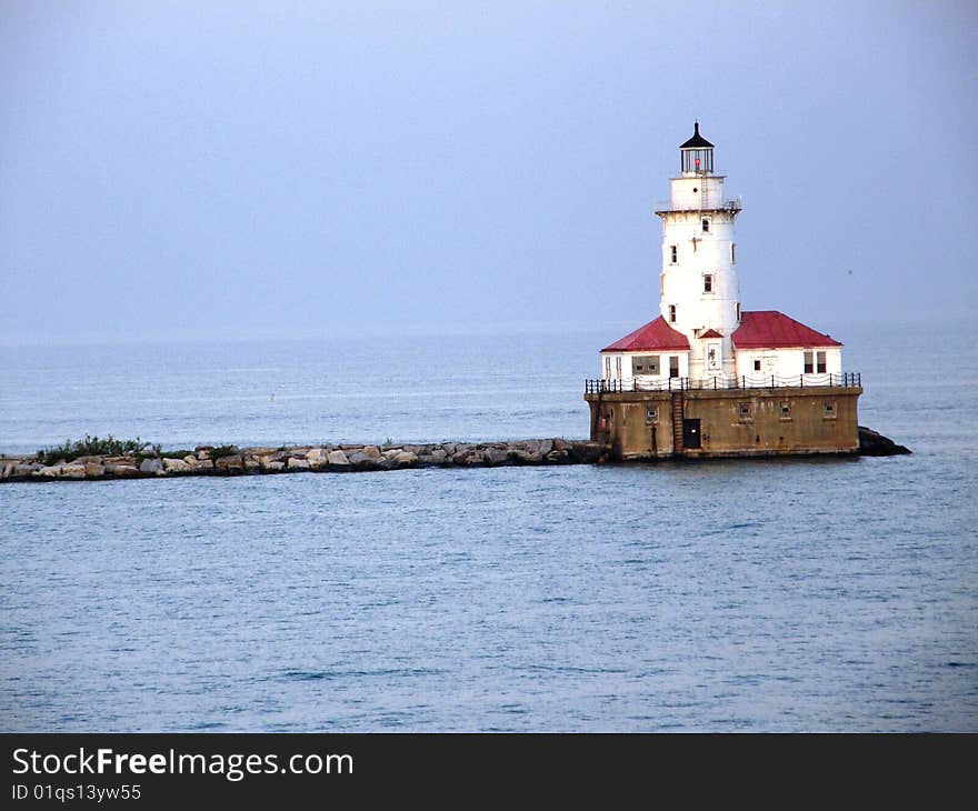 A lighthouse at the end of a pier on a lake