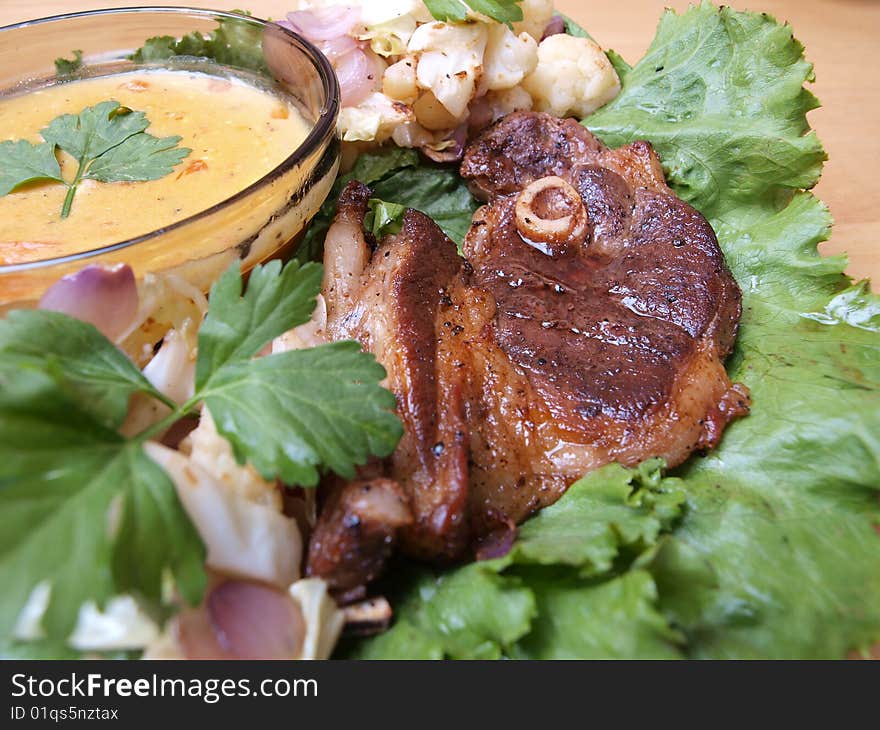 Close-up juicy tantalizing roasted lamb chop on salad bed and mustard gravy picture one. Close-up juicy tantalizing roasted lamb chop on salad bed and mustard gravy picture one