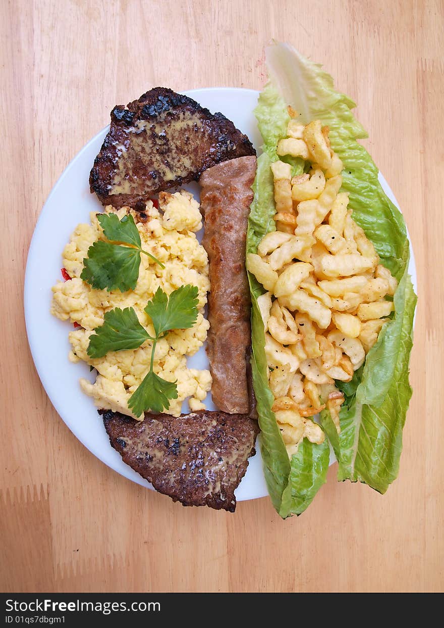 Plate of roasted beef cutlets salad fries eggs and bread on wood table surface picture two. Plate of roasted beef cutlets salad fries eggs and bread on wood table surface picture two