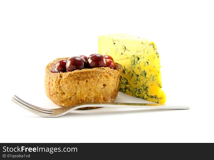 Pork pie and slice of blue cheese with fork and clipping path on a white background. Pork pie and slice of blue cheese with fork and clipping path on a white background