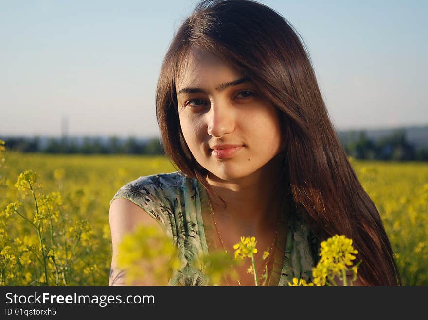 A beautiful girl standing on a field with yellow canola. A beautiful girl standing on a field with yellow canola