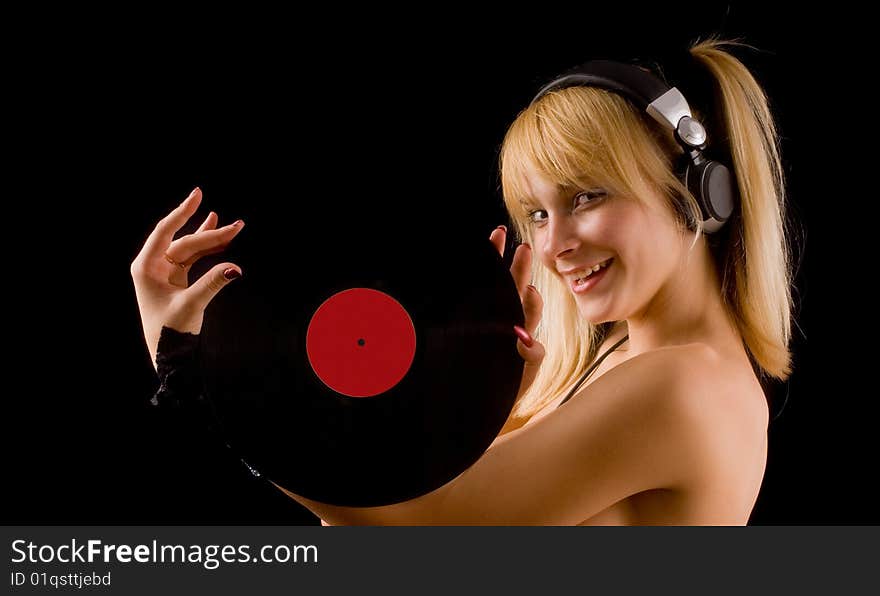 Sexual young girl with a vinyl records in hand and headphones on a black background. Sexual young girl with a vinyl records in hand and headphones on a black background