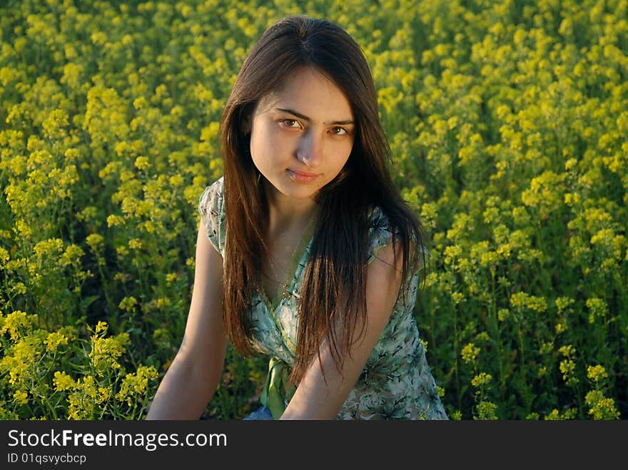 A beautiful girl standing on a field with yellow canola. A beautiful girl standing on a field with yellow canola