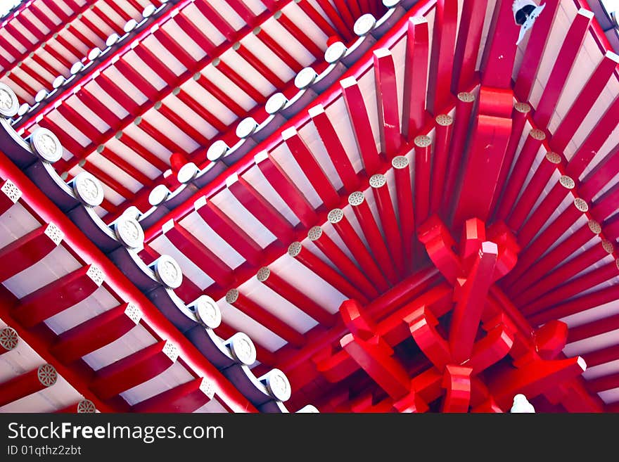 A red wooden structure made entirely of wooden poles