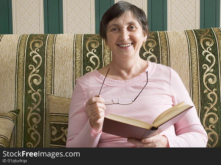 Aged woman reading a book and smiling. Aged woman reading a book and smiling